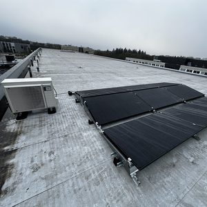 Deze installatie toont zonnepanelen op een plat dak, met een airconditioner vlakbij.