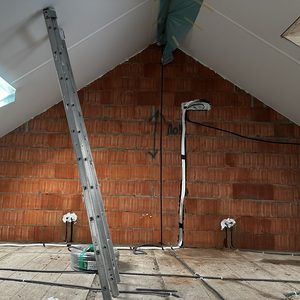 De afbeelding toont de voorbereidende werkzaamheden voor een airconditioning installatie, met leidingen en aansluitingen zichtbaar op de muur.