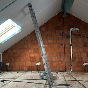 De afbeelding toont een voorbereidingsfase voor een airconditioninginstallatie met leidingen en aansluitpunten op de muur.