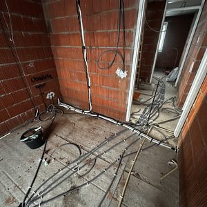 De installatie toont een onvoltooid aircosysteem met leidingen en elektrische bedrading in een bouwomgeving.