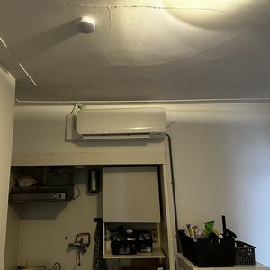 Deze afbeelding toont een onlangs geïnstalleerde airconditioningseenheid aan de muur in een binnenruimte.