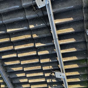 De foto toont een montagesysteem voor zonnepanelen op een dak, met kabels en connectors zichtbaar.
