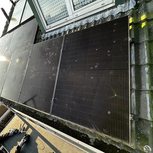 Een installatie van zonnepanelen op een dak, met zichtbare zonnepanelen en een technicus die bezig is met de installatie.