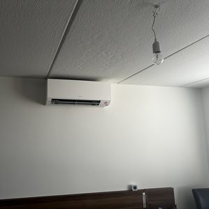 Een moderne airconditioningseenheid hangt aan de muur in een interieur, waardoor koude lucht efficiënt kan worden verspreid.