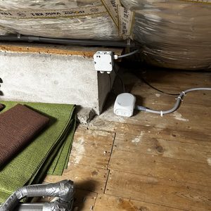 De afbeelding toont een airco-installatie met leidingen en bedrading in een ruimte, omgeven door isolatiemateriaal.