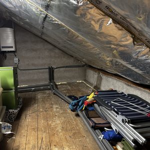 Een installatie met leidingen en een airconditioner in een geïsoleerde ruimte onder het dak.
