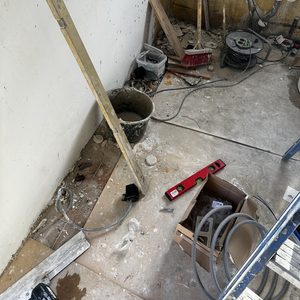 Een installatieproject van een meterkast met diverse voorbereidingen en materialen nabij een wand.