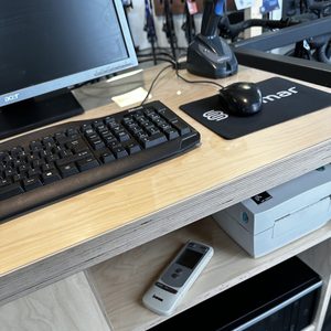 De afbeelding toont een airco-installatie met bedieningselementen en een systeemkast onder een bureau.