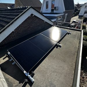 De foto toont een zonnepaneel installatie op een plat dak met een helder blauwe lucht op de achtergrond.