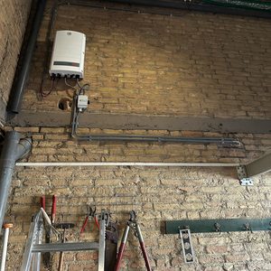 De afbeelding toont een omvormer voor zonnepanelen, samen met leidingen die de elektrische verbindingen weergeven.