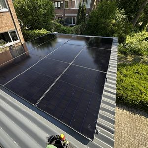 De foto toont een installatie van zonnepanelen op een hellend dak, wat bijdraagt aan duurzame energieoplossingen.