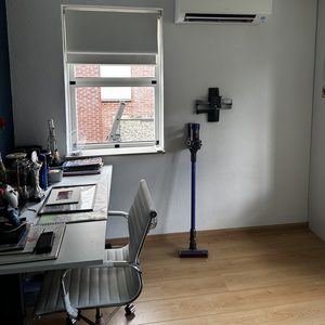 Instapunt van een split-airco-systeem gemonteerd op een muur in een werkkamer met uitzicht op een raam.