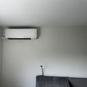 Een wandmodel airconditioningseenheid is geïnstalleerd, met leidingen die langs de muur lopen.