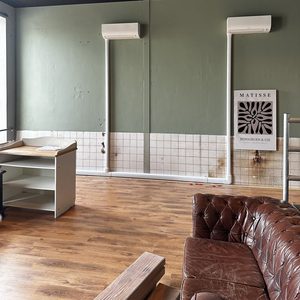 Twee airconditioningunits geïnstalleerd aan de muur, klaar voor gebruik in een ruimte met houten vloer.