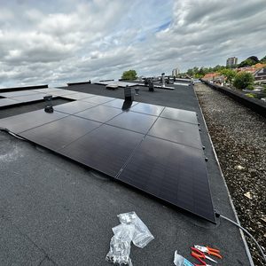 Een installatie van zonnepanelen op een plat dak, zichtbaar met verschillende elementen en gereedschappen voor de montage.