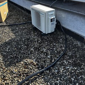 De foto toont een geïnstalleerde airconditioning eenheid op een dak, naast zonnepanelen.