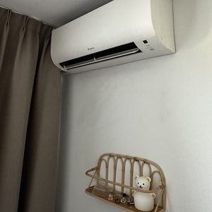 Een wandairconditioner, perfect geïnstalleerd boven een decoratief rekje. Compact ontwerp voor efficiënte koeling.
