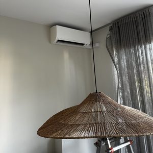De afbeelding toont een bevestigde airconditioning unit aan de muur, met een plafondlamp en een zichtbare elektrische aansluiting.