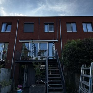 De foto toont een woning met een airconditioninginstallatie aan de buitenzijde, zichtbaar boven de deur.