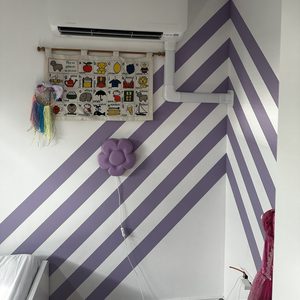 Een wandmodel airconditioningsysteem dat is geïnstalleerd in een kamer met gekleurde muren en decoratieve elementen.