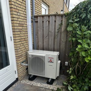 Extern geplaatste airco-installatie bij een woning, ontworpen voor efficiënte koeling en verwarming.