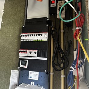 De afbeelding toont een meterkast met aansluitingen en schakelaars voor een airco-installatie, met een overzicht van de bedrading en stroomafname.