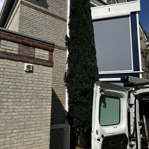 Een buitenunit van een airconditioningsysteem geïnstalleerd aan de gevel van een huis.