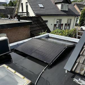 Een zonnepaneleninstallatie is zichtbaar op het dak van een woning, met elektrische bekabeling en een goed onderhouden dakoppervlak.
