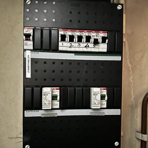 De afbeelding toont een meterkast met verschillende schakelaars en een label voor zonnepanelen.