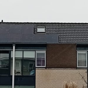 De foto toont een installatie van zonnepanelen op een hellend dak van een woning.